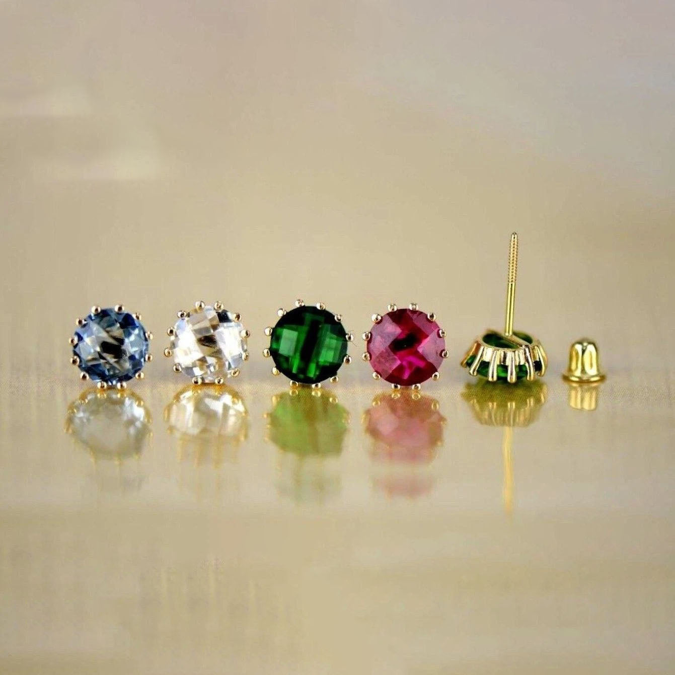 Set of colorful gemstone earrings on a reflective surface