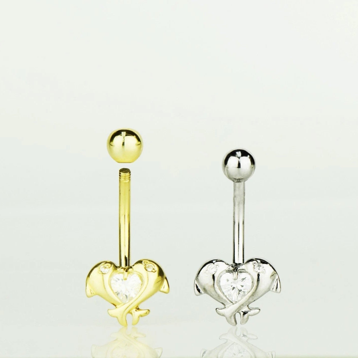 Gold and silver heart-shaped belly button rings on a white background
