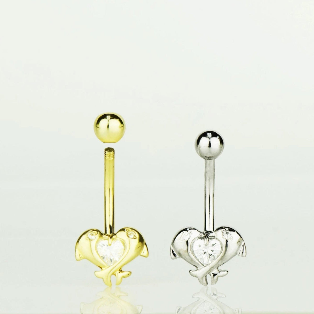 Gold and silver heart-shaped belly button rings on a white background
