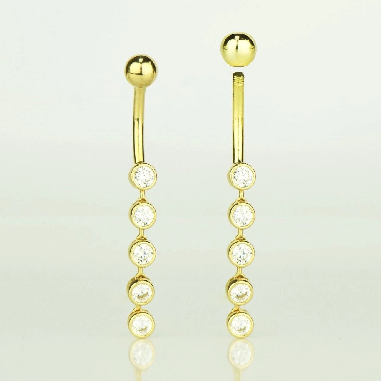 Gold earrings with clear gemstones on a light gray background