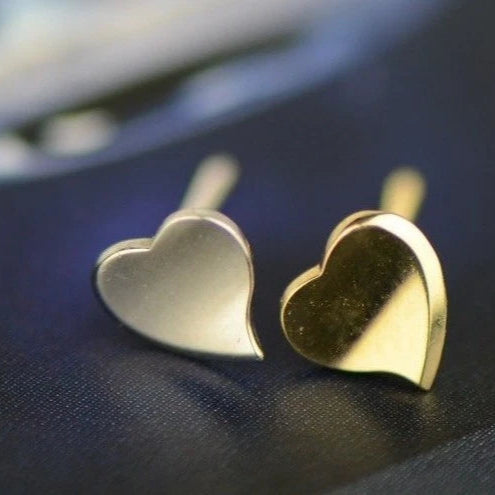 Gold heart-shaped earrings on a dark fabric background